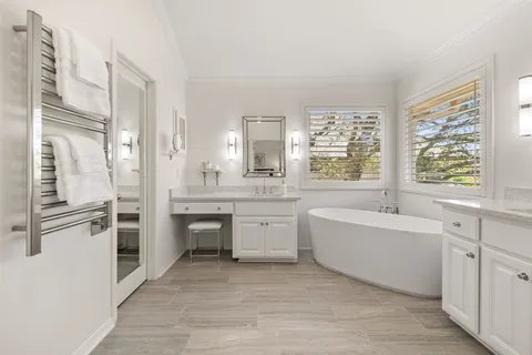 a large white bathroom with a large tub sink and mirror