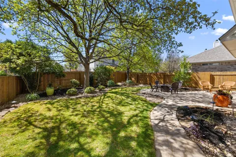 a backyard of a house with table and chairs under an umbrella