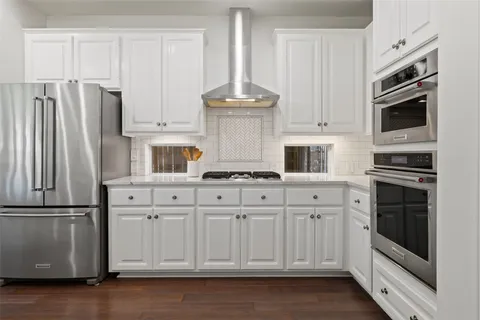 a kitchen with stainless steel appliances granite countertop a refrigerator oven stove a microwave oven with white cabinets