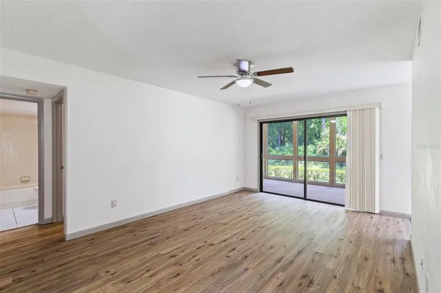 a view of empty room with wooden floor and fan