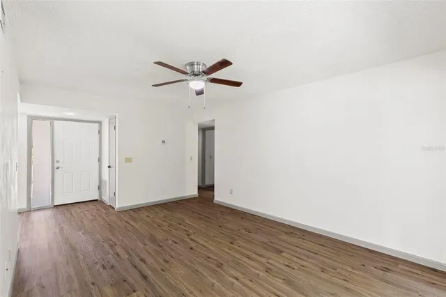 an empty room with wooden floor and a ceiling fan