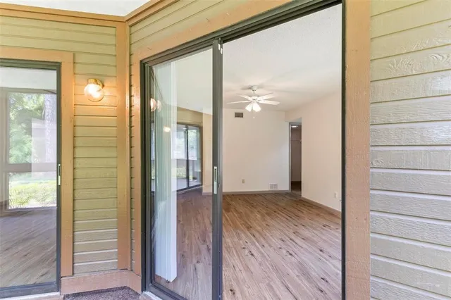 a view of a hallway with wooden floor and a bathroom