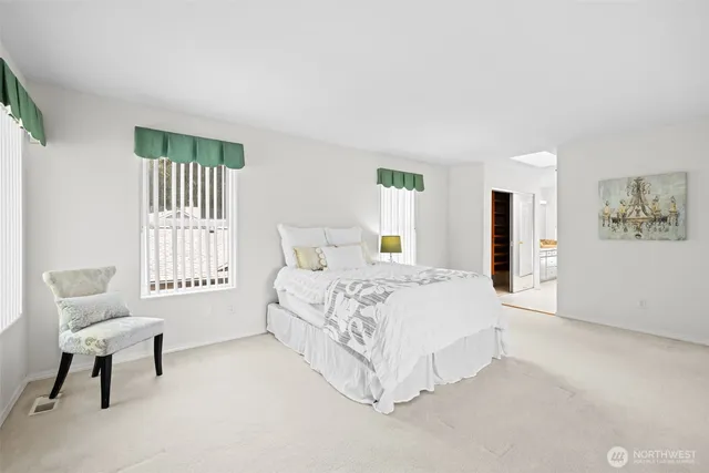 a spacious bedroom with a bed chair and window