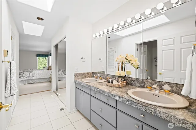 a bathroom with a sink double vanity granite tub shower and mirror