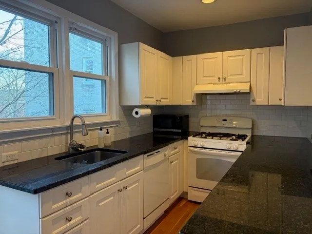 a kitchen with granite countertop white cabinets and a sink