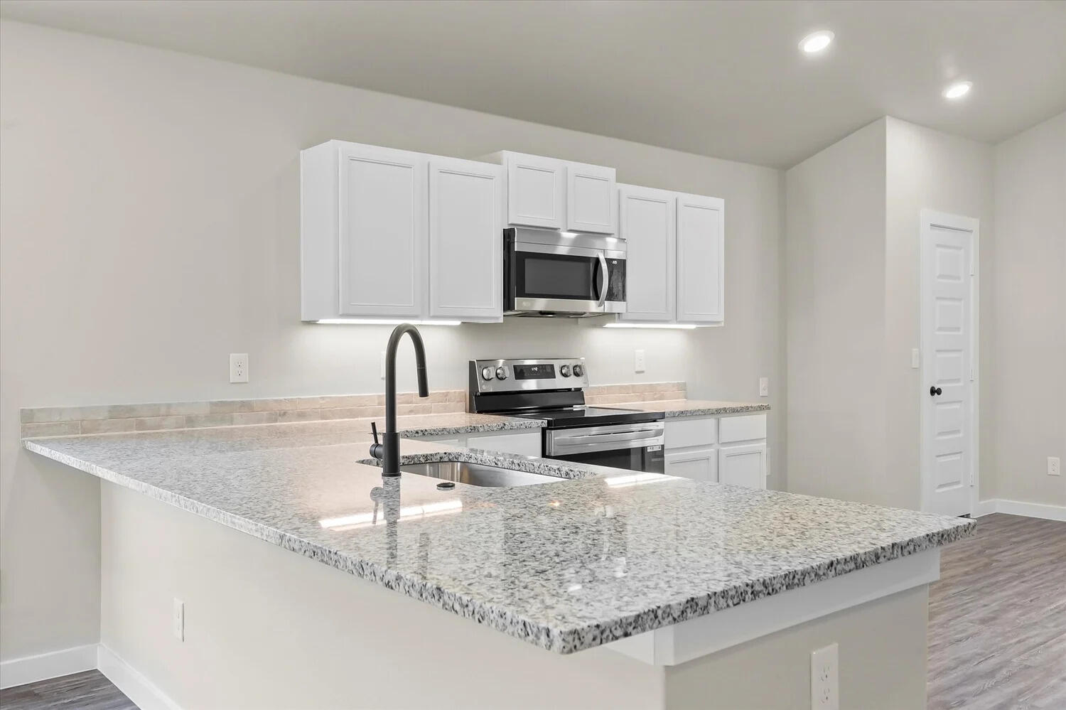 7446 29th Street Lubbock, TX 79407 - Photo 3 of 11 a kitchen with granite countertop a sink a stove and a microwave