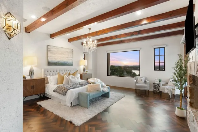 a spacious bedroom with a bed a chandelier and flat screen tv