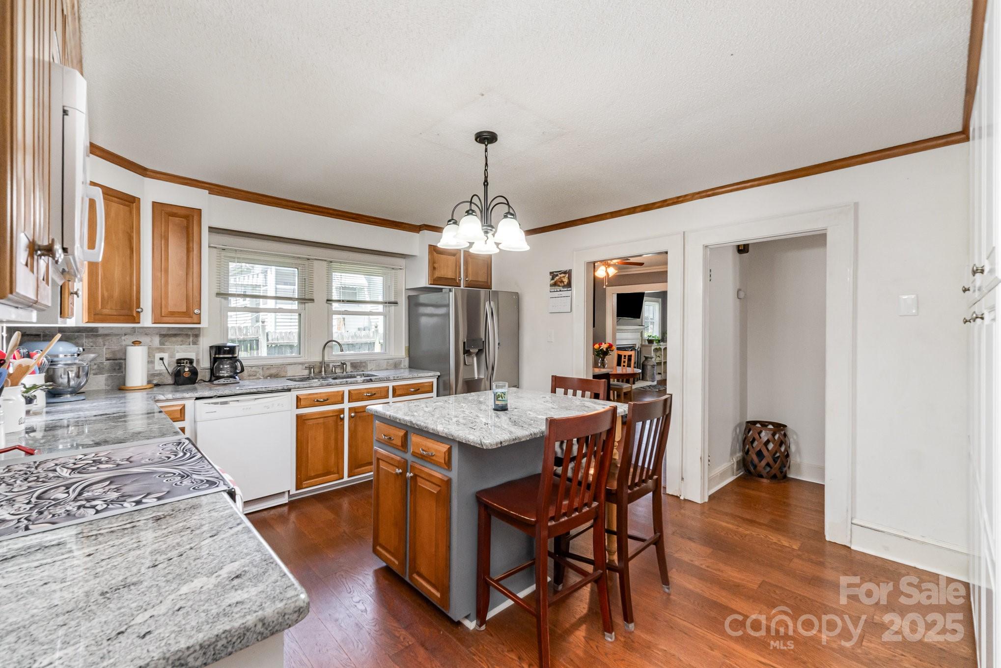 1306 Brantley Road Kannapolis, NC 28083 - Photo 12 of 29 a kitchen with a stove a sink dishwasher and a dining table with wooden floor