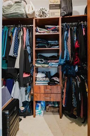 a view of walk in closet with clothes and shoes