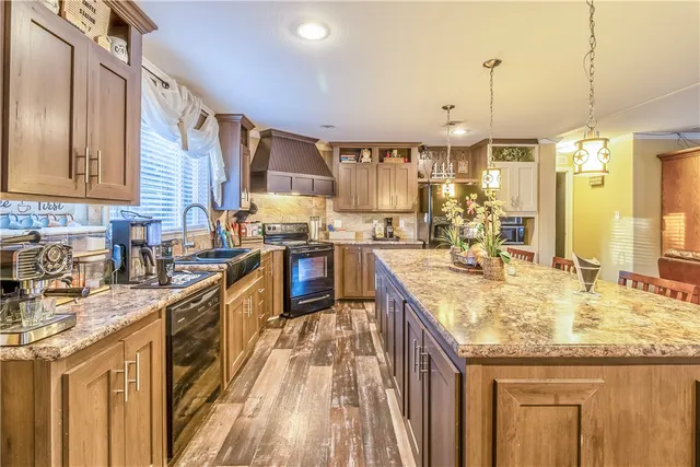 a kitchen with stainless steel appliances granite countertop a sink a stove and a wooden floors