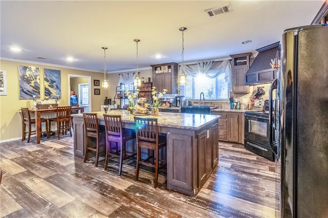 a kitchen with stainless steel appliances kitchen island granite countertop a table chairs and a refrigerator