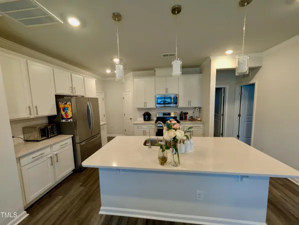 a kitchen with stainless steel appliances a dining table chairs refrigerator and microwave
