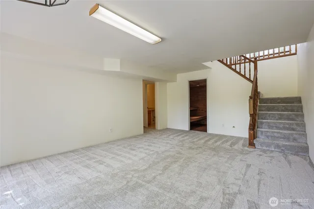 a view of an empty room with stairs and a window