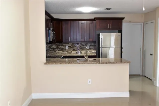 a kitchen with kitchen island a counter top space cabinets and stainless steel appliances