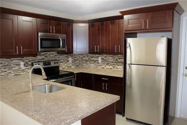 a kitchen with stainless steel appliances granite countertop a refrigerator a stove a sink and a microwave