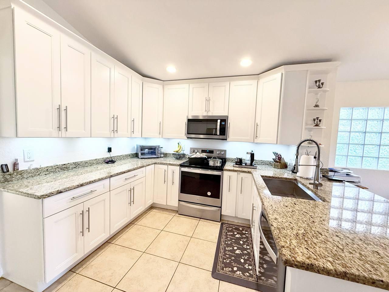 1067 Big Torch Street Riviera Beach, FL 33407 - Photo 7 of 23 a large kitchen with granite countertop a stove sink and cabinets