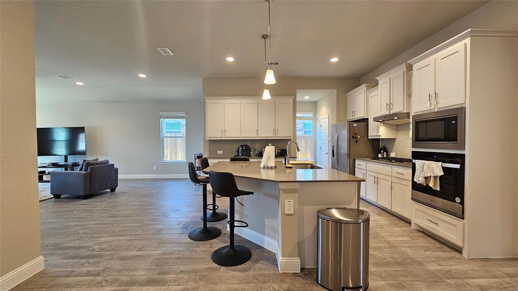 1405 Razorbill Road Denton, TX 76205 - Photo 31 of 40 a kitchen with kitchen island granite countertop a sink appliances and cabinets