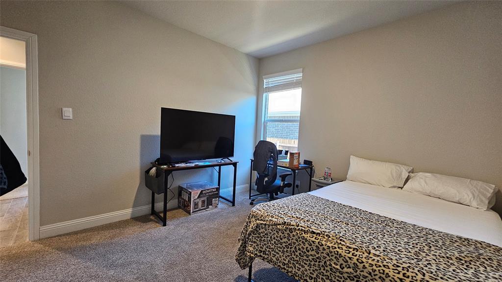 1405 Razorbill Road Denton, TX 76205 - Photo 37 of 40 a bedroom with a bed and a flat screen tv