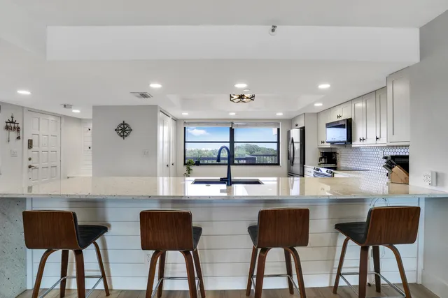 a kitchen with stainless steel appliances granite countertop a dining table chairs and a refrigerator