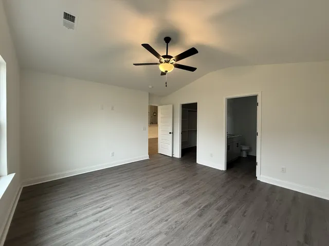 an empty room with wooden floor and a ceiling fan