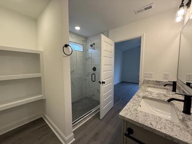 a bathroom with a granite countertop sink a mirror and shower