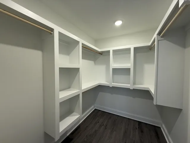 an empty room with chandelier fan and windows