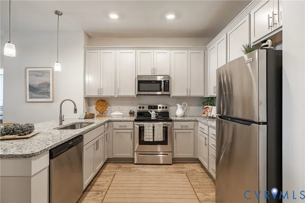 a kitchen with stainless steel appliances granite countertop a stove a refrigerator and a sink