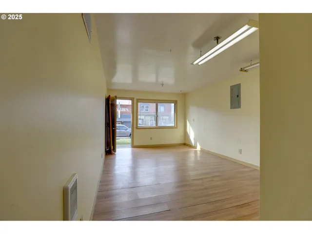 a view of an empty room with a window and wooden floor