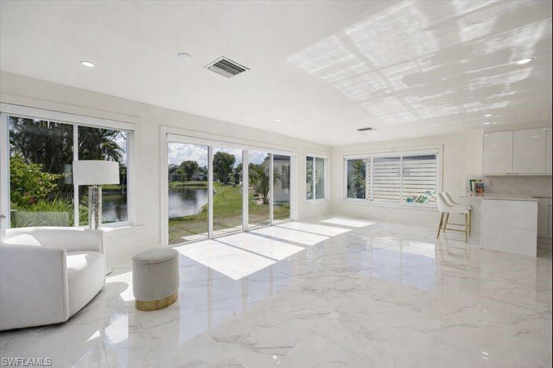 16 Knights Bridge Road Naples, FL 34112 - Photo 7 of 18 Unfurnished living room with light marble finish flooring, recessed lighting, a water view, and plenty of natural light