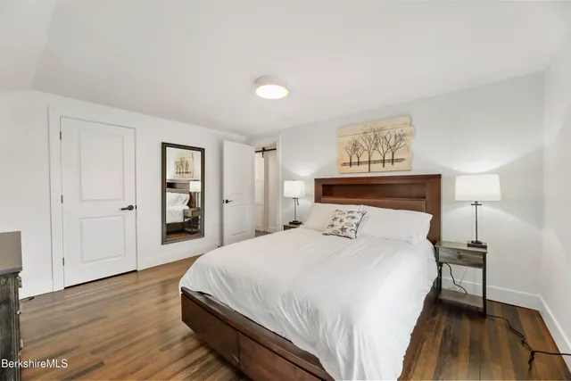 a spacious bedroom with a bed and wooden floor