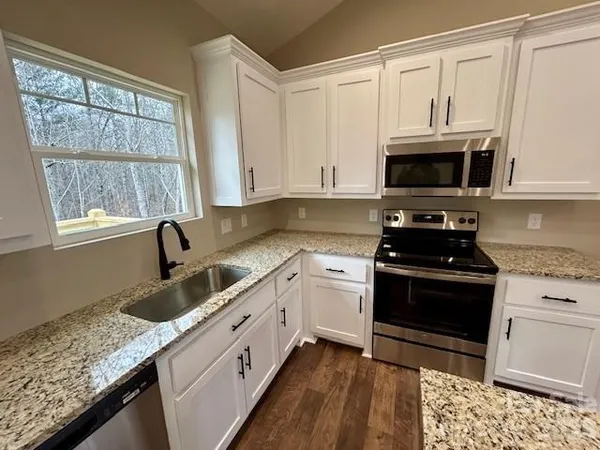 a kitchen with granite countertop a sink a stove and cabinets