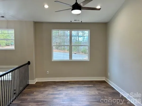 an empty room with wooden floor fan and windows