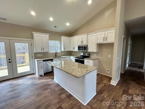 a large kitchen with stainless steel appliances granite countertop a stove a sink dishwasher and a refrigerator with wooden floor