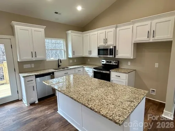 a kitchen with granite countertop a sink dishwasher stove and cabinets with wooden floor