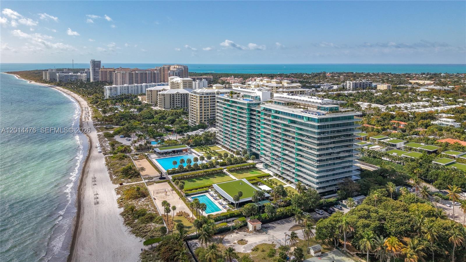 360 Ocean Drive, Unit 1106S Key Biscayne, FL 33149 - Photo 50 of 67 Aerial Beachfront Overview – A sweeping aerial view showcases the building’s beachfront setting, resort-style pool areas, landscaped grounds, and the shoreline stretching along the coast. The elevated perspective highlights the property’s connection to both the ocean and surrounding coastal neighborhood.