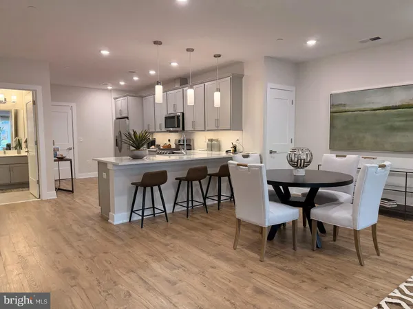 a kitchen with stainless steel appliances kitchen island granite countertop a stove a refrigerator a table and chairs with wooden floor