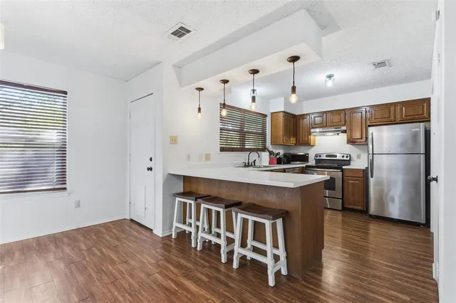 a kitchen with stainless steel appliances granite countertop a refrigerator a stove a sink dishwasher and a refrigerator with wooden floor