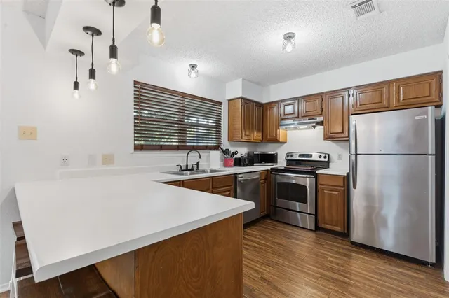 a kitchen with a refrigerator a stove top oven a sink and dishwasher with wooden floor