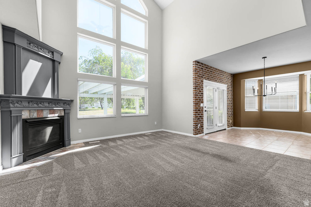 1417 Blacksmith Lane Draper, UT 84020 - Photo 10 of 57 Vaulted ceiling living area featuring a fireplace with decorative mantel, expansive picture windows, and gray patterned carpeting