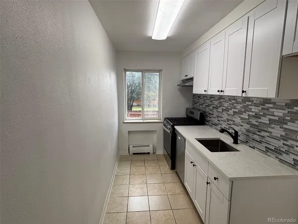 a kitchen with a sink a stove top oven and cabinets