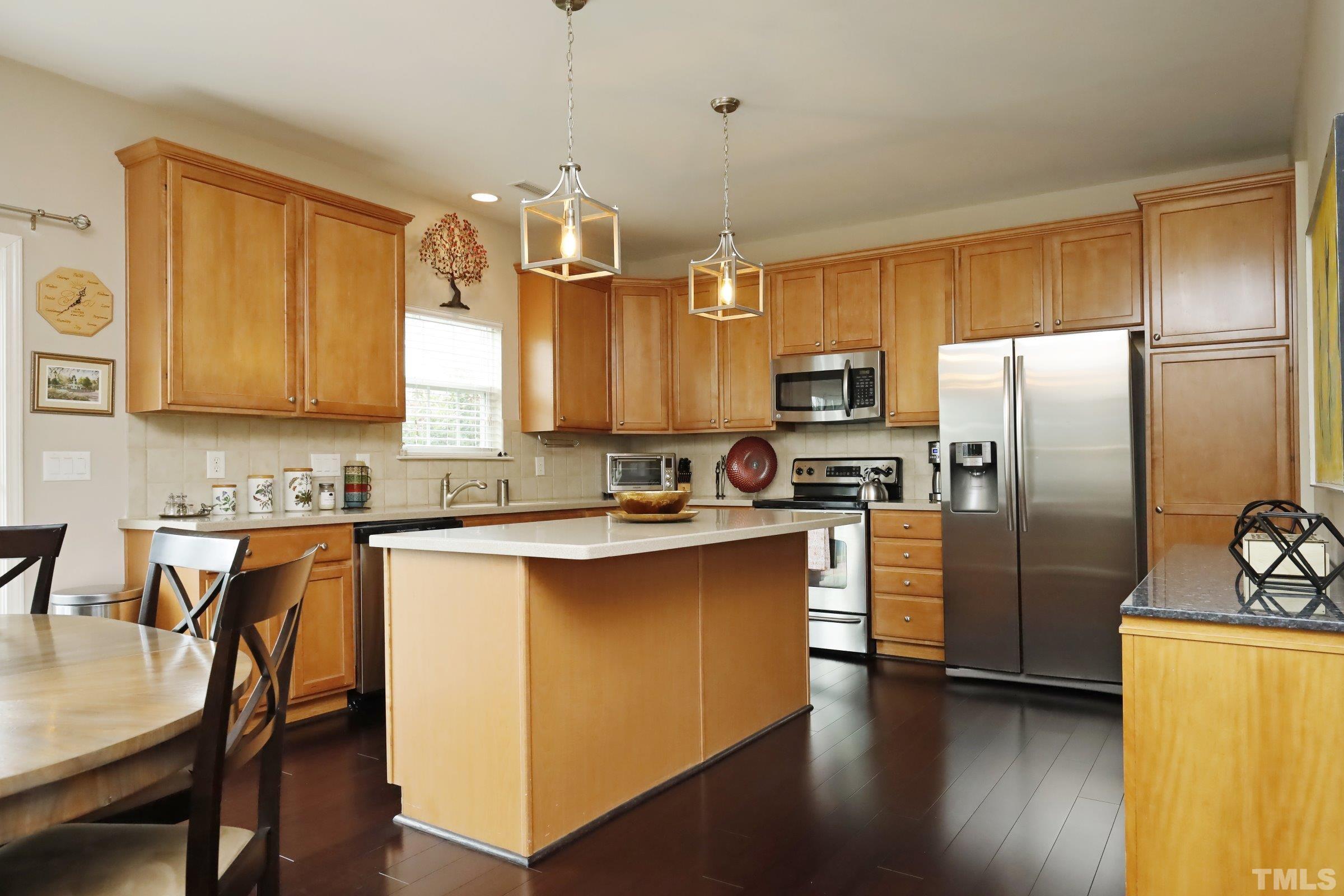 5325 Glass Ridge Road Raleigh, NC 27616 - Photo 13 of 42 a kitchen with stainless steel appliances granite countertop a refrigerator a sink dishwasher a stove and a dining table with wooden floor
