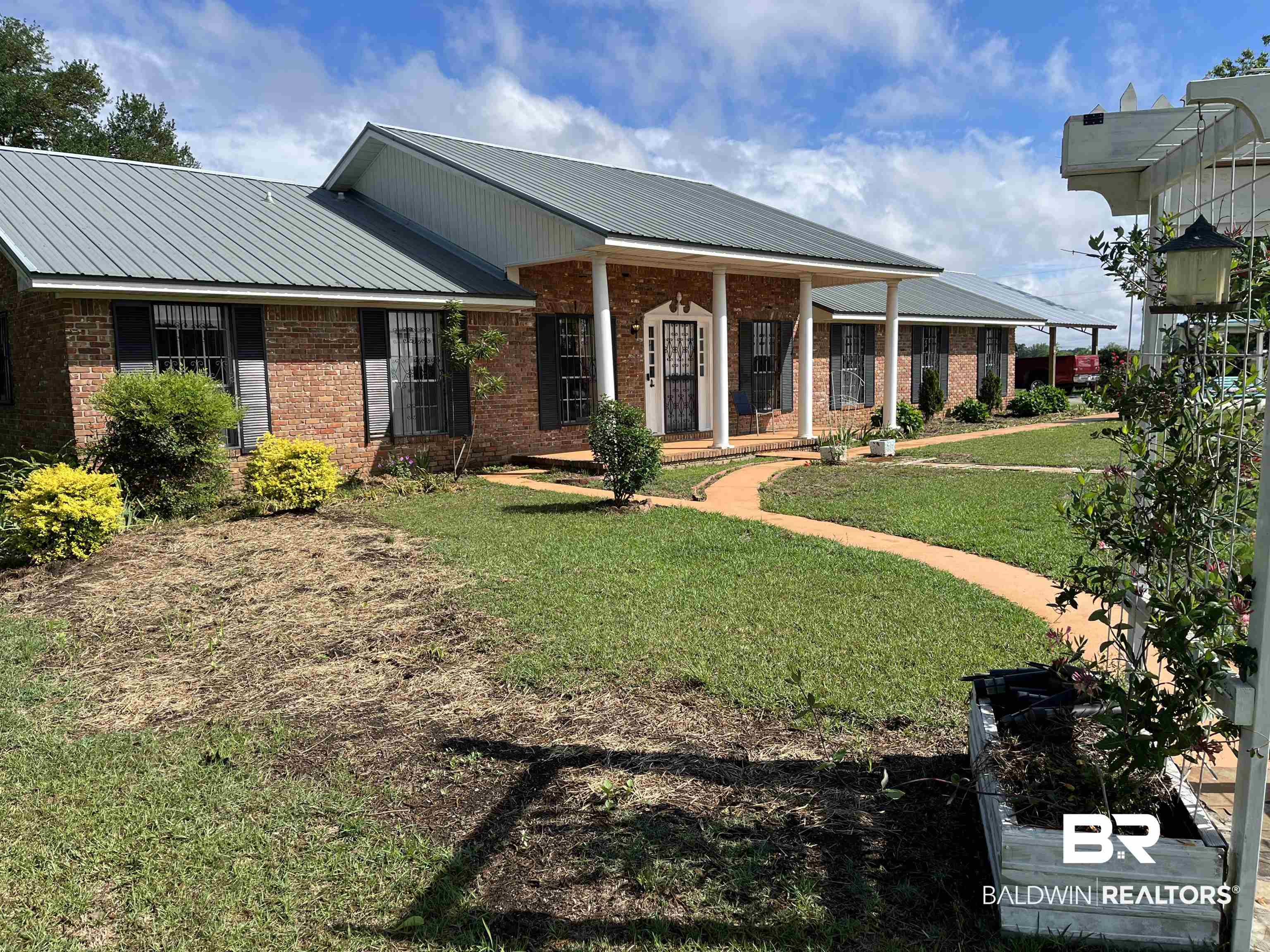 3791 Robinsonville Road Atmore, AL 36502 - Photo 1 of 47 Brick exterior with a gray metal roof, featuring a covered entry porch with white columns