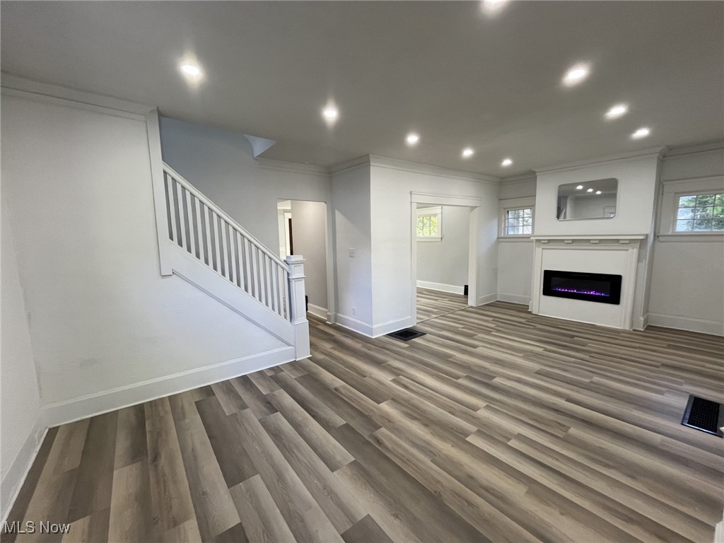 3264 Altamont Road Cleveland, OH 44118 - Photo 6 of 32 Unfurnished living room with stairs, ornamental molding, recessed lighting, dark wood-looking floors, and a glass covered fireplace