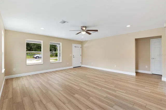 a view of an empty room with a window and wooden floor