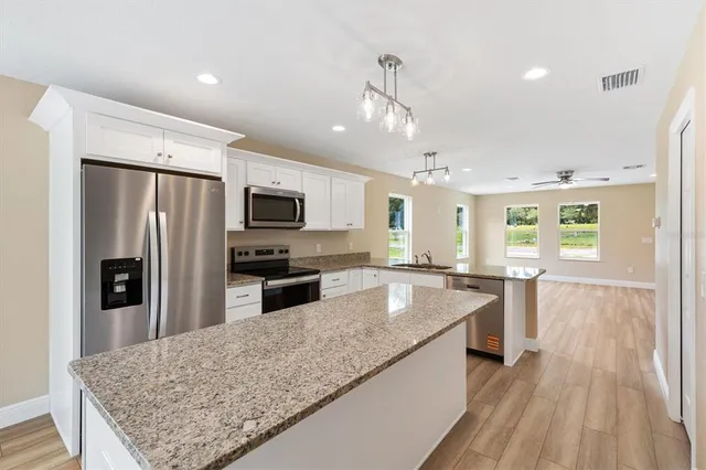 a large kitchen with kitchen island a large counter top stainless steel appliances and cabinets