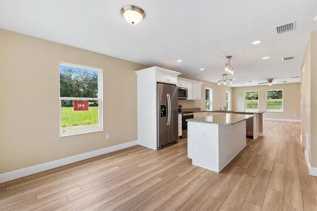 a kitchen with kitchen island wooden floors stainless steel appliances and window