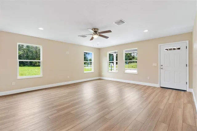 a view of an empty room with a window and wooden floor