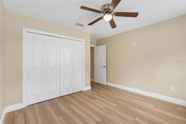 an empty room with wooden floor closet and fan