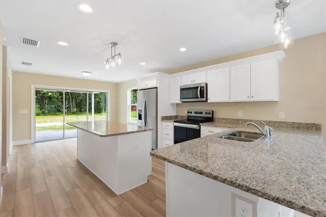 a kitchen with granite countertop a stove a sink a microwave and refrigerator