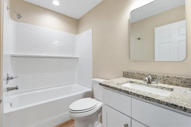 a bathroom with a granite countertop sink a toilet and bathtub